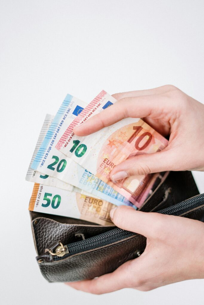 pexels-photo-3943745-3943745 Close-up of a hand holding euro banknotes of different denominations, taken from a black wallet.